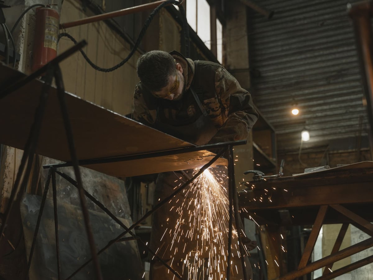 An angle grinder throwing a fan of sparks off a welded steel frame &mdash; representative imagery, not a specific Late Night Fabrication job