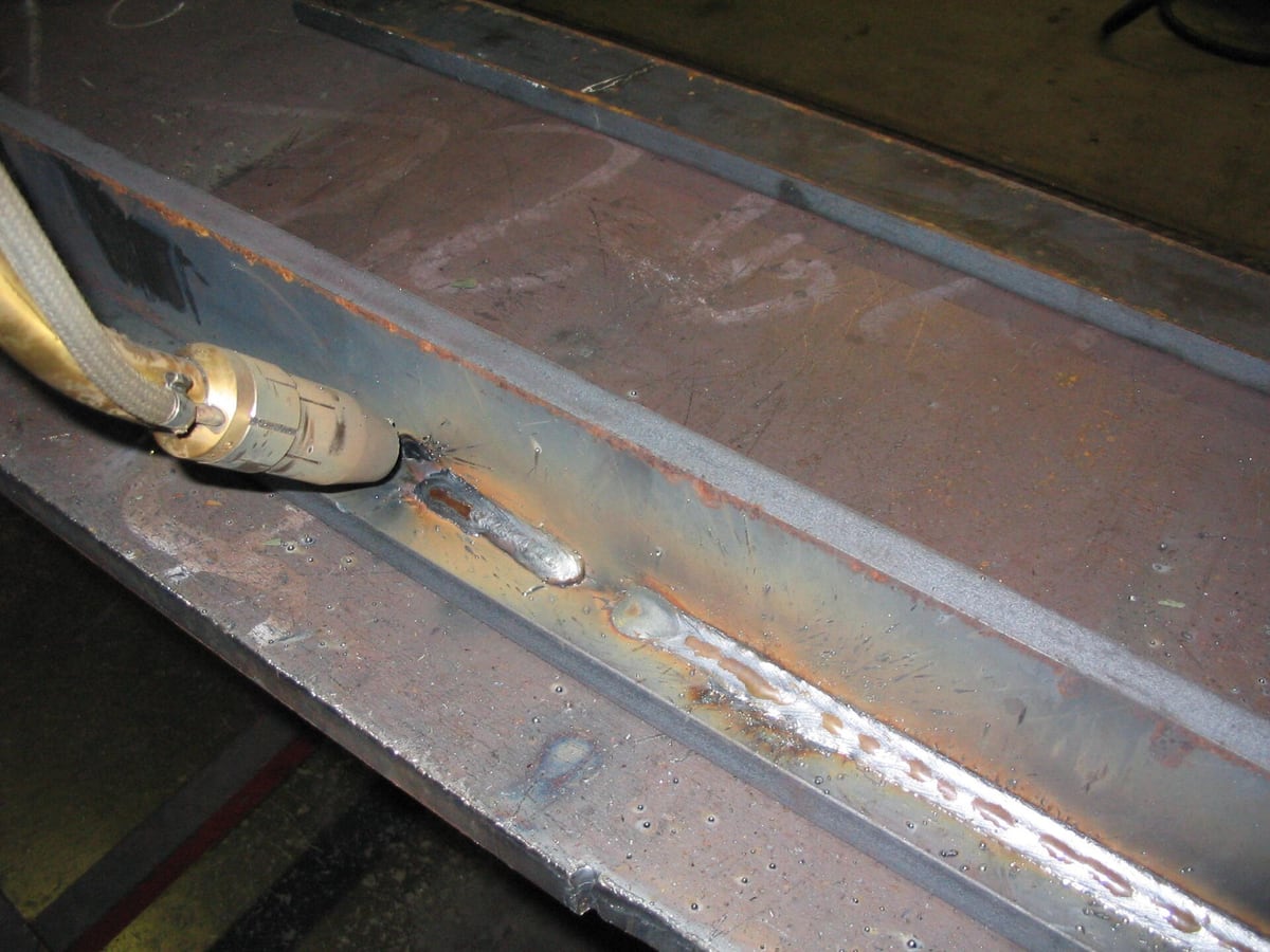 A close view of a finished fillet weld seam joining two steel plates, heat tint along the bead &mdash; representative imagery, not a specific Late Night Fabrication job